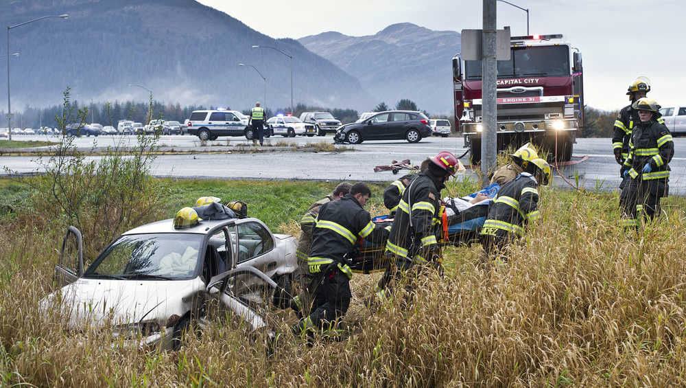 A woman is carried from the driver's seat of a sedan to an ambulance by Capital City Fire/Rescue personnel after a two-vehicle accident at the intersection of Egan Drive and Old Dairy Road in October 2015.