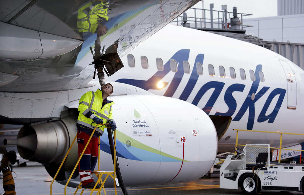 FILE - In this Monday, Nov. 14, 2016, photo, fueling manager Jarid Svraka looks on as he fuels an Alaska Airlines Boeing 737-800 jet with a new, blended alternative jet fuel, at Seattle-Tacoma International Airport in SeaTac, Wash. On Tuesday, Dec. 6, 2016, Alaska Airlines said it has won government approval to buy rival Virgin America after agreeing to reduce its flight-selling partnership with American Airlines. (AP Photo/Elaine Thompson, File)