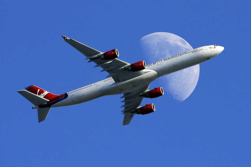 FILE - In this Sunday, Aug. 23, 2015, file photo, a Virgin Atlantic passenger plane crosses a waxing gibbous moon on its way to the Los Angeles International Airport, in Whittier, Calif. On Tuesday, Dec. 6, 2016, Alaska Airlines said it has won government approval to buy rival Virgin America after agreeing to reduce its flight-selling partnership with American Airlines. (AP Photo/Nick Ut, File)