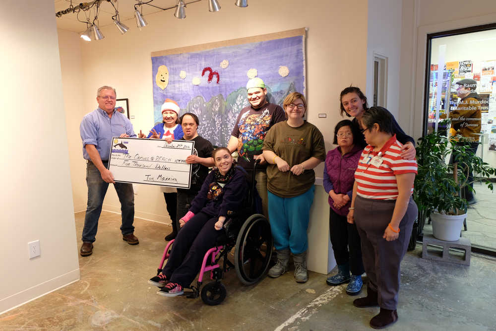 Tom Manning presents a $5,000 check to the Canvas artists in the downtown art gallery.