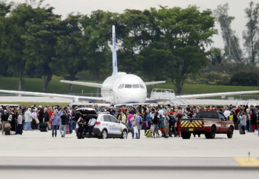 People stand on the tarmac at the Fort Lauderdale-Hollywood International Airport after a shooter opened fire inside a terminal of the airport, killing several people and wounding others before being taken into custody, Friday.
