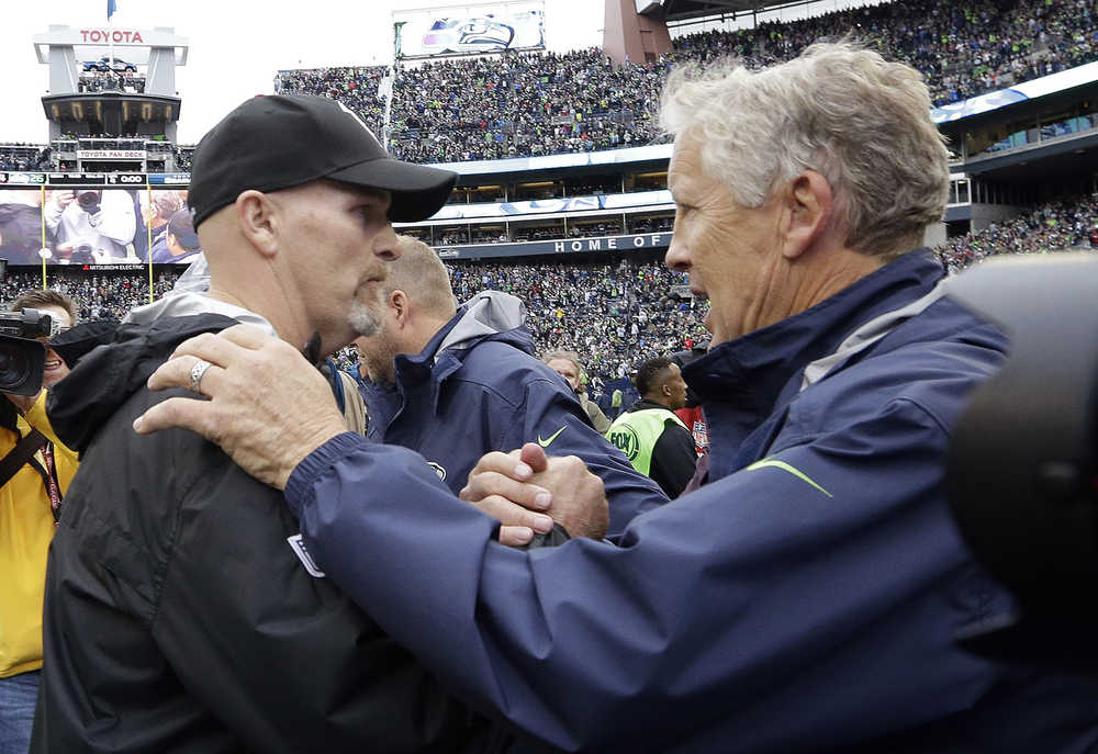 FILE - In this Oct. 16, 2016, file photo, Seattle Seahawks coach Pete Carroll, right, greets Atlanta Falcons coach Dan Quinn after an NFL football game in Seattle. Quinn and the Falcons play the Seahawks this week in the playoffs; Quinn is a former Seahawks defensive coordinator. (AP Photo/Elaine Thompson, File)