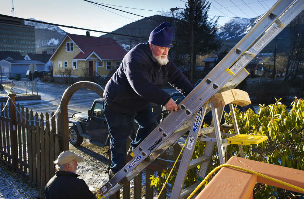 Jim Nelson climbs a ladder held by his neighbor Jim Fowler on Monday, Jan. 9, 2017, as he replaces asphalt shingles blown off his roof by last week's wind storm.