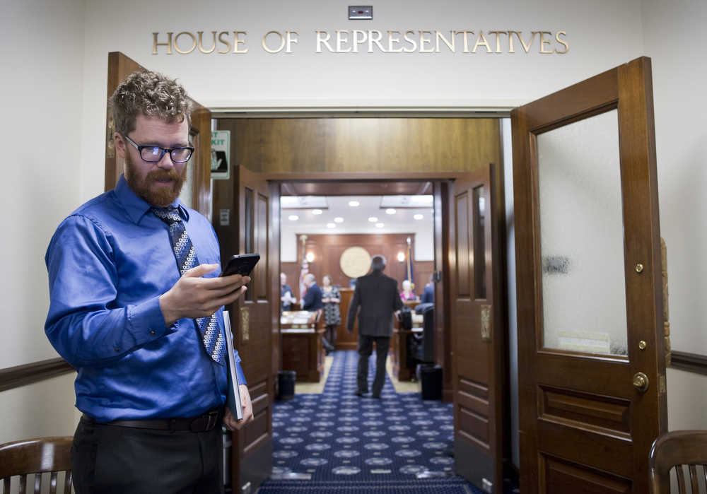 Rep. Justin Parish, D-Juneau, checks his phone before a practice session in the House of Representatives with other new legislators at the Capitol on Friday, Jan. 13, 2017.
