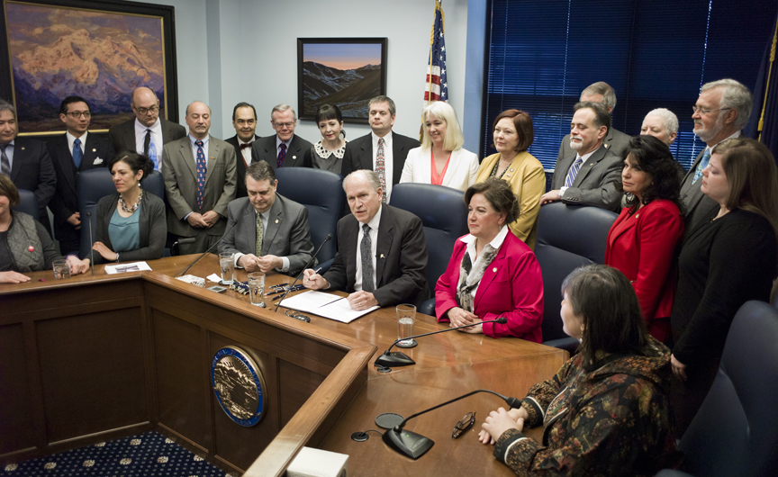 Legislators line up behind Gov. Bill Walker as he signs Senate Bill 23 into law at the Capitol on Monday. The bill gives legal protection to those who administer the life-saving heroin antidote called Naloxone, or Narcan. Sen. Johnny Ellis, D-Anchorage, sitting left, and Rep. Lynn Gattis, R-Wasilla, sitting right, sponsored the bill in the Senate and House.