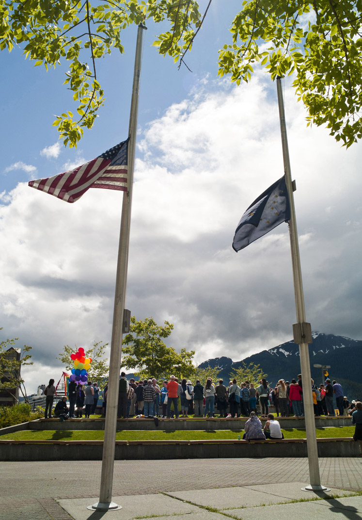 Flags fly at half-staff as Juneau residents attend a noon vigil Monday at Marine Park for the victims of the Orlando shootings over the weekend.