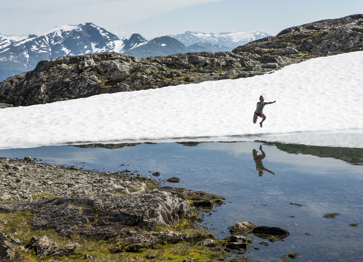 Solana Ashe jumps into a snow melt pond at the top of Mount Jumbo on Monday.