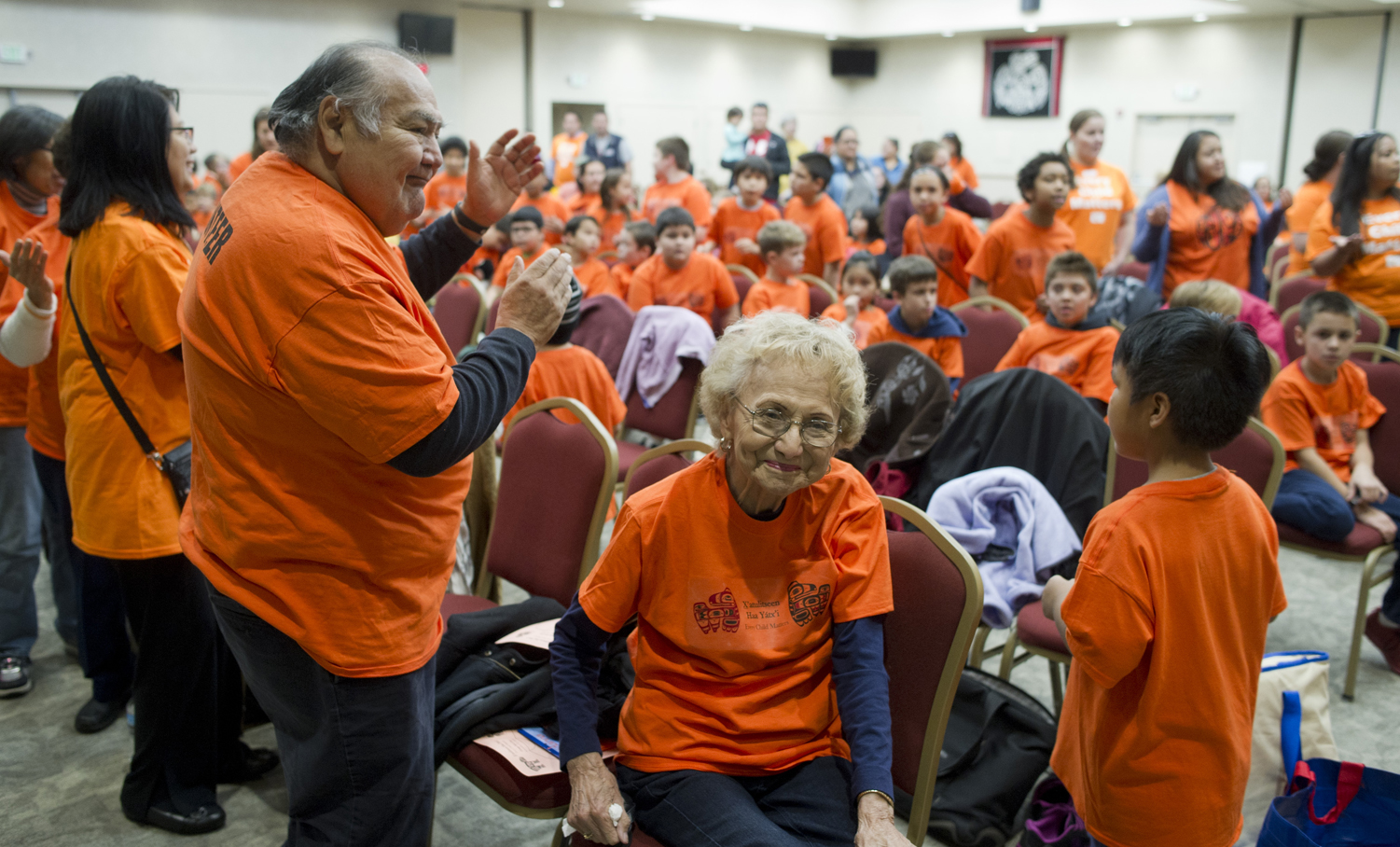 Elders, including David Katzeek, left, and Selina Everson, watch students enter Elizabeth Peratrovich Hall for Orange Shirt Day on Friday.