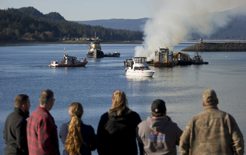 Harbor staff watch as the Consul D tugboat burns outside of Aurora Harbor on Monday. No one was aboard when the fire was reported. The vessel is owned by Steve Hamilton.