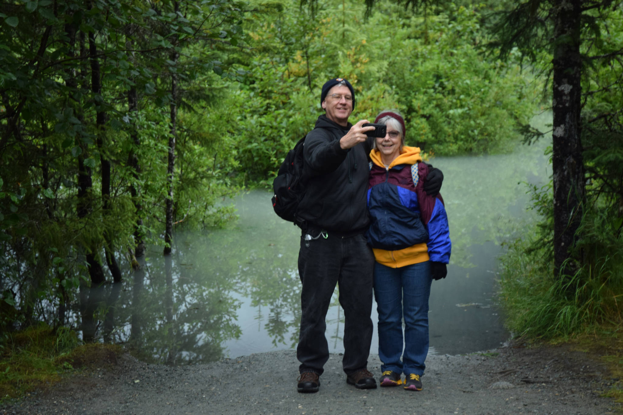 Steve and JoAnne Zemanek, from Dayton, Ohio, pose for selfie at a flooded impass on Nugget Falls Trail. Flooding on the Mendenhall River and lake is expected to peak today. (Kevin Gullufsen | Juneau Empire)
