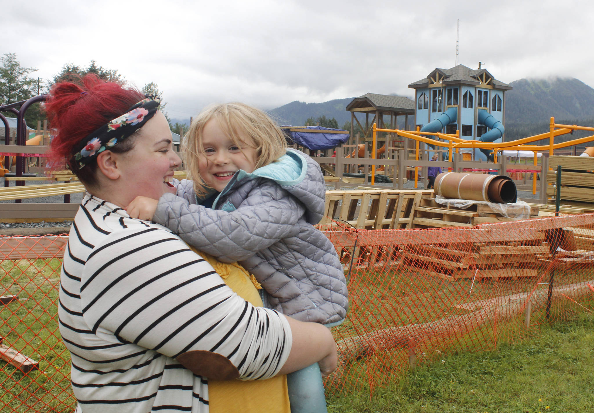 Lilah Gaguine, 4, laughs as her mother Becca holds her near Project Playground on the first day of the community build, Aug. 8, 2018. Lilah saved up her allowance for a year to donate to the rebuild, and was invited as an honorary volunteer. (Alex McCarthy | Juneau Empire)