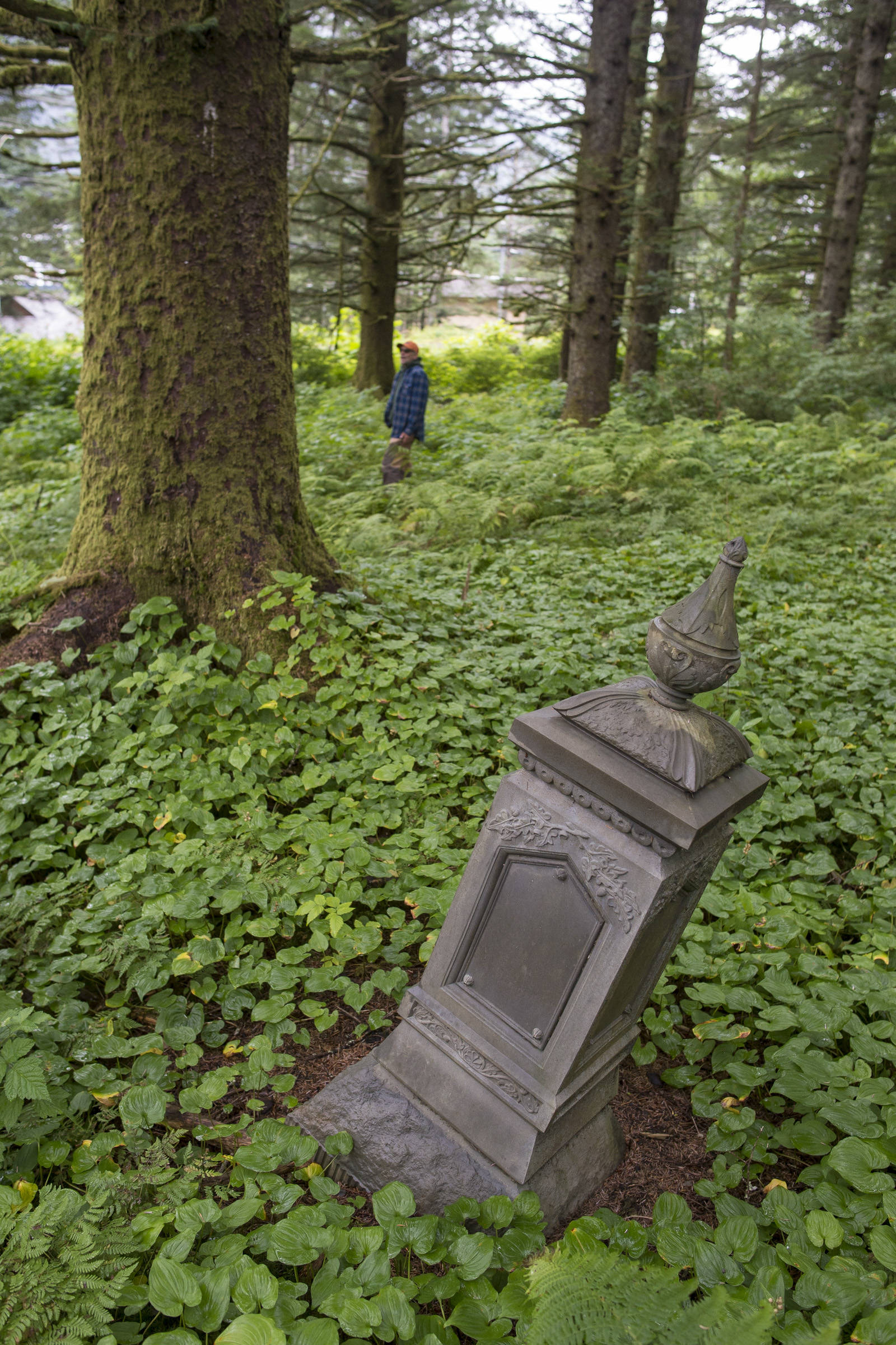 A headstone from 1905 lays askew as Ben Patterson, the city’s park maintenance supervisor, gives a tour of the cemetery sections in Douglas on Monday, August 13, 2018. (Michael Penn | Juneau Empire)