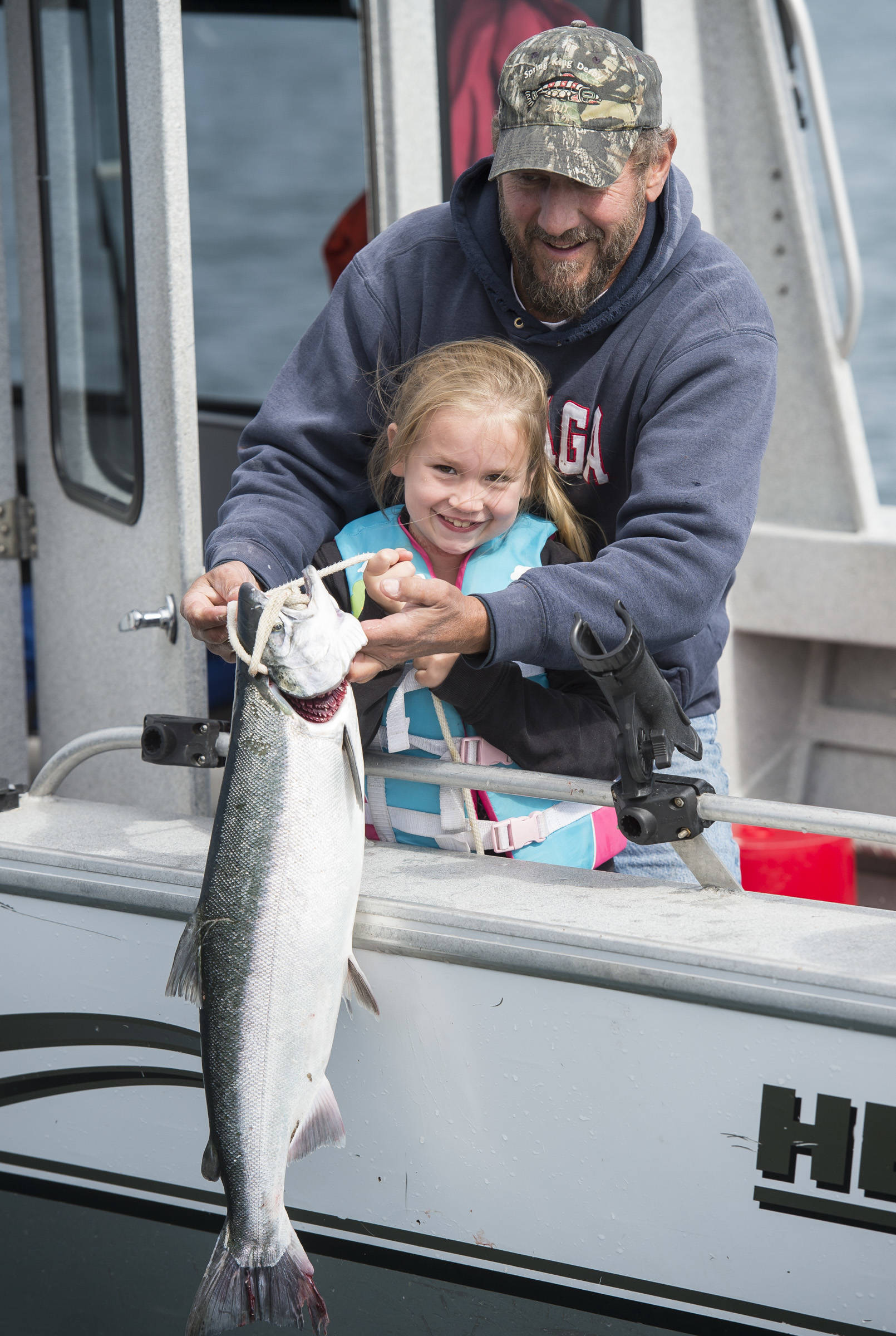 Lily Abby, 7, gets help holding up a silver salmon by her grandfather, Scott Guenther during the 72nd Annual Golden North Salmon Derby on Friday, August 17, 2018, sponsored by the Territorial Sportsmen. (Michael Penn | Juneau Empire)