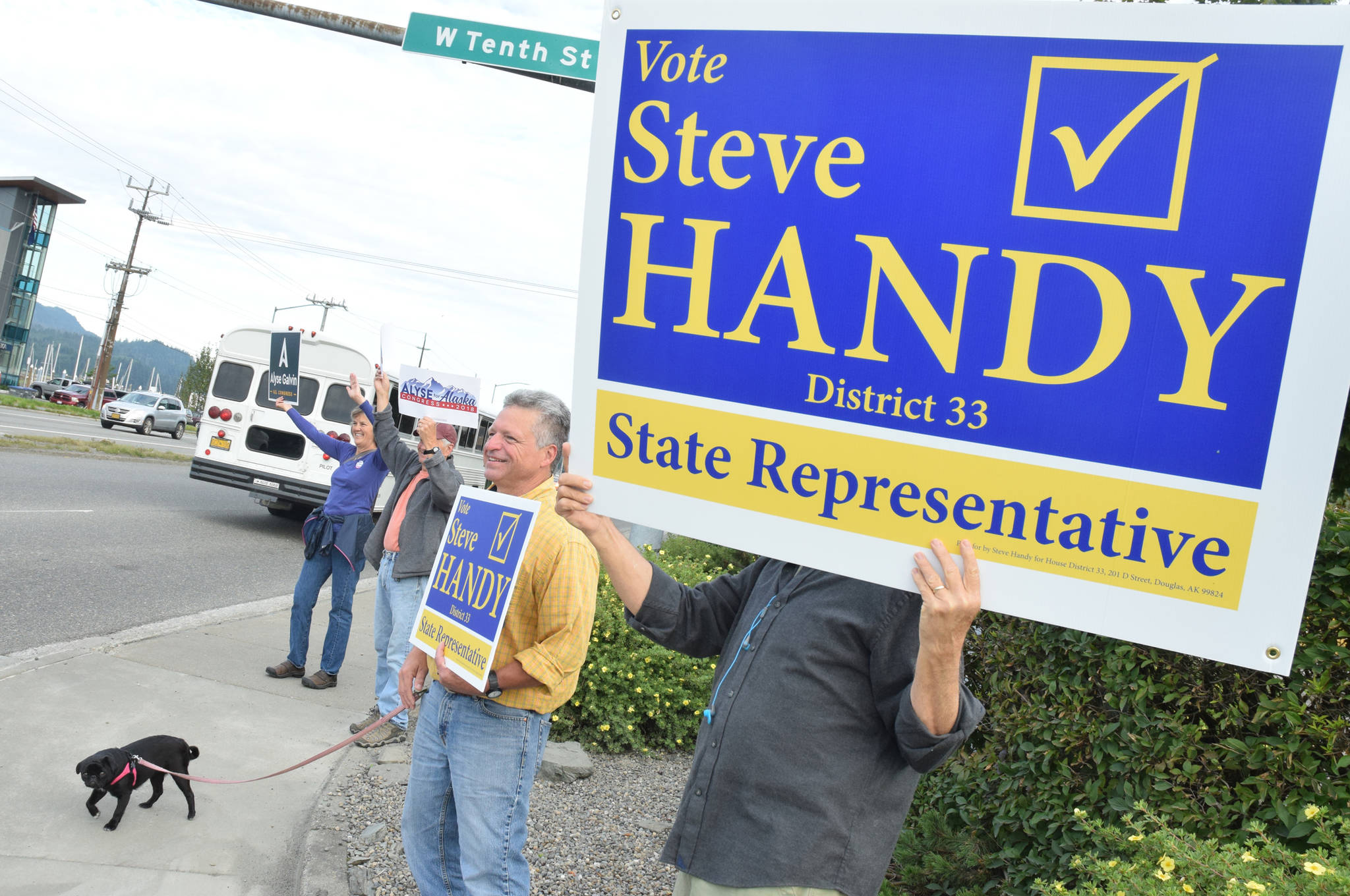 Steve Handy, Democratic candidate for House District 33, is accompanied by his pug, Panda, while waving signs at the Douglas Bridge intersection on Tuesday, Aug. 21, 2018. (James Brooks | Juneau Empire)