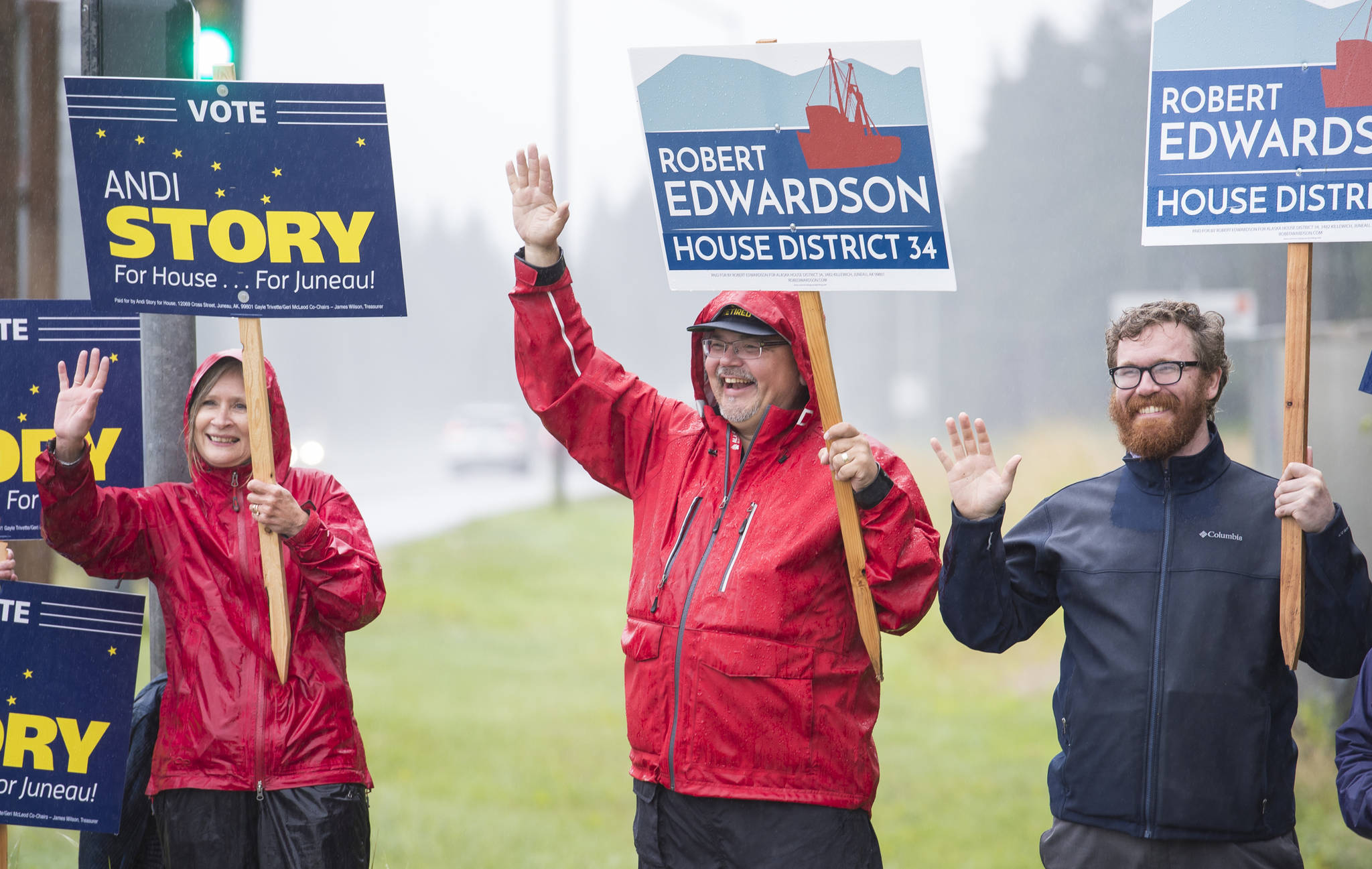 House District 34 candidates Andi Story, left, and Rob Edwardson, center, wave campaign signs with Rep. Justin Parish, D-Juneau, at Egan Drive and Glacier Highway on Tuesday, Aug. 21, 2018. (Michael Penn | Juneau Empire)
