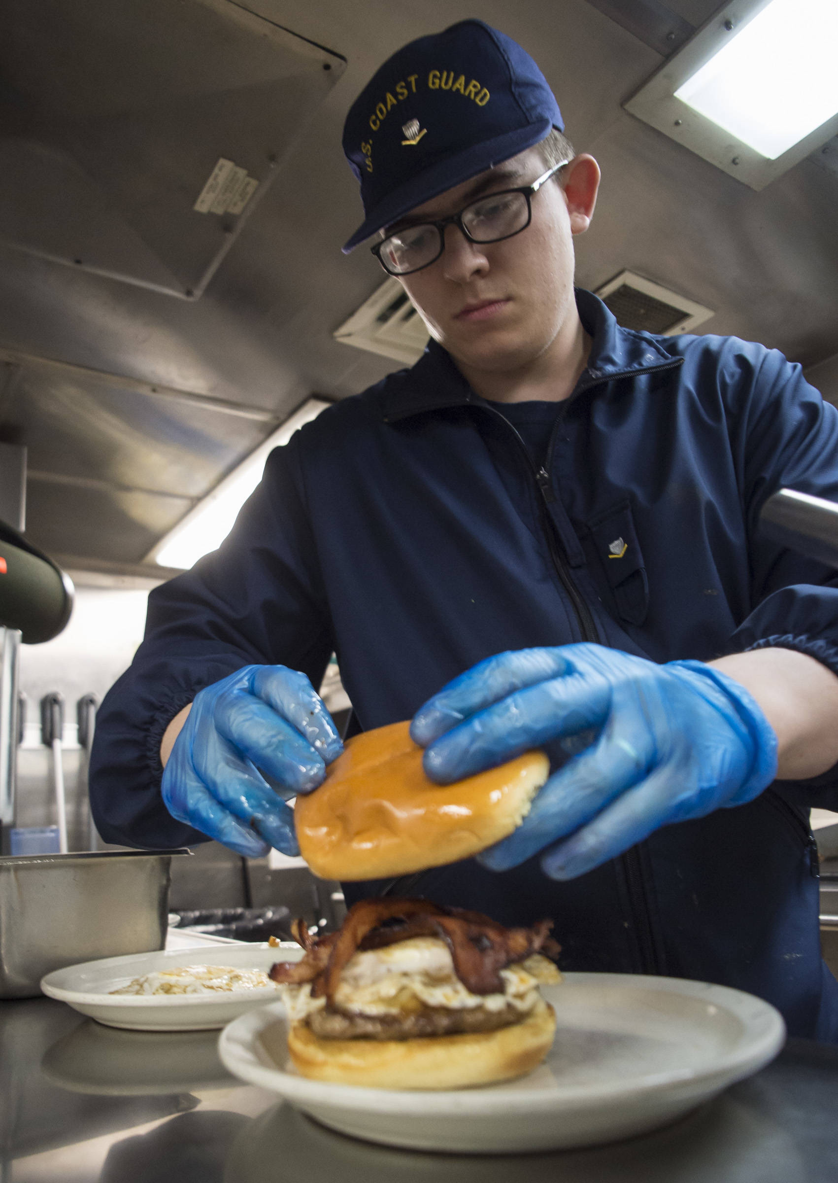 Chef Berkeley Scott, of the buoy tender Hickory, prepares two burgers to be judged on Thursday, Aug. 23, 2018. (Michael Penn | Juneau Empire)