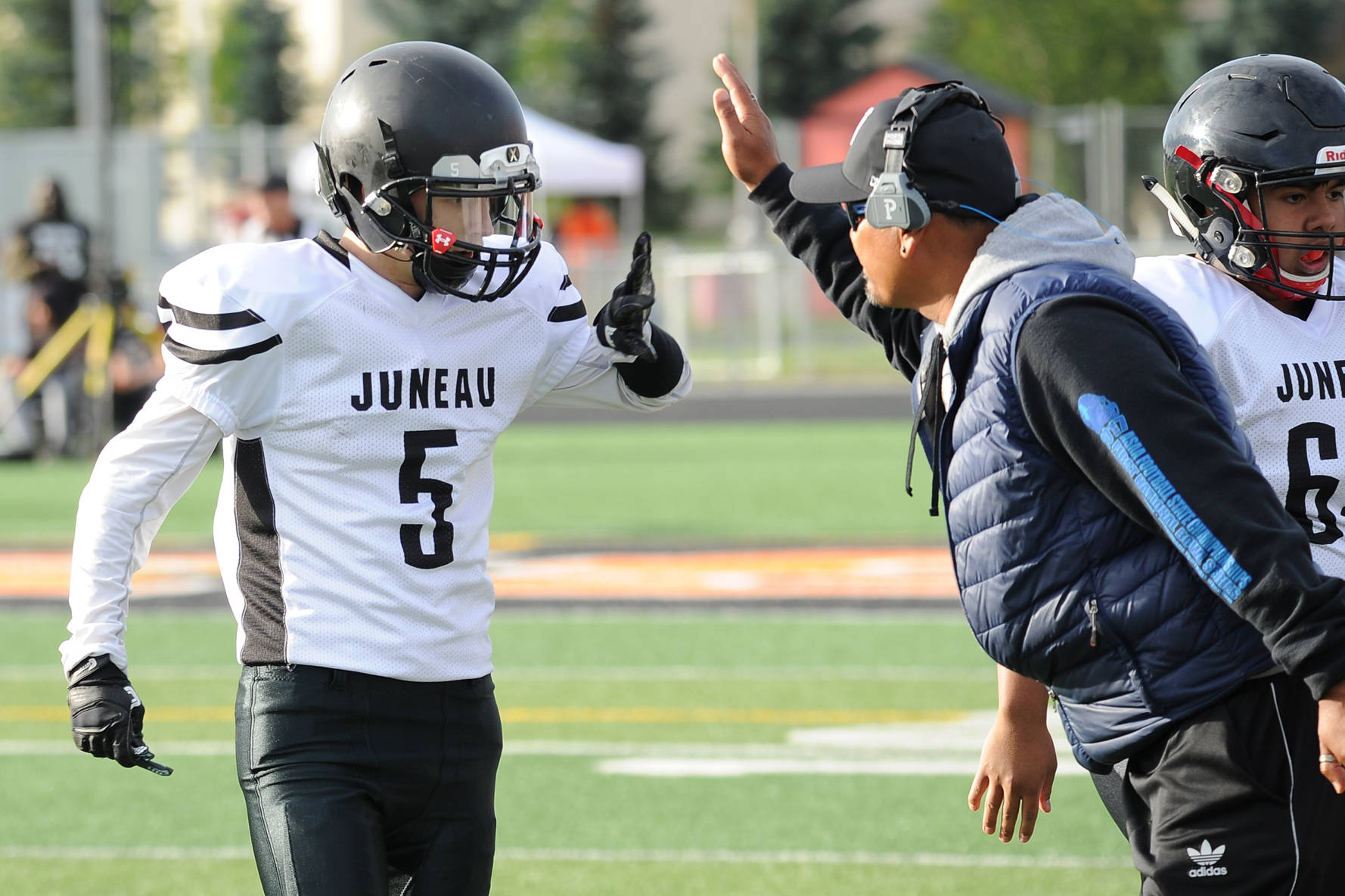 Hansel Hinckle is congratulated by coach Randy Quinto following his interception return for a touchdown last Saturday. (Michael Dineen | For the Juneau Empire)