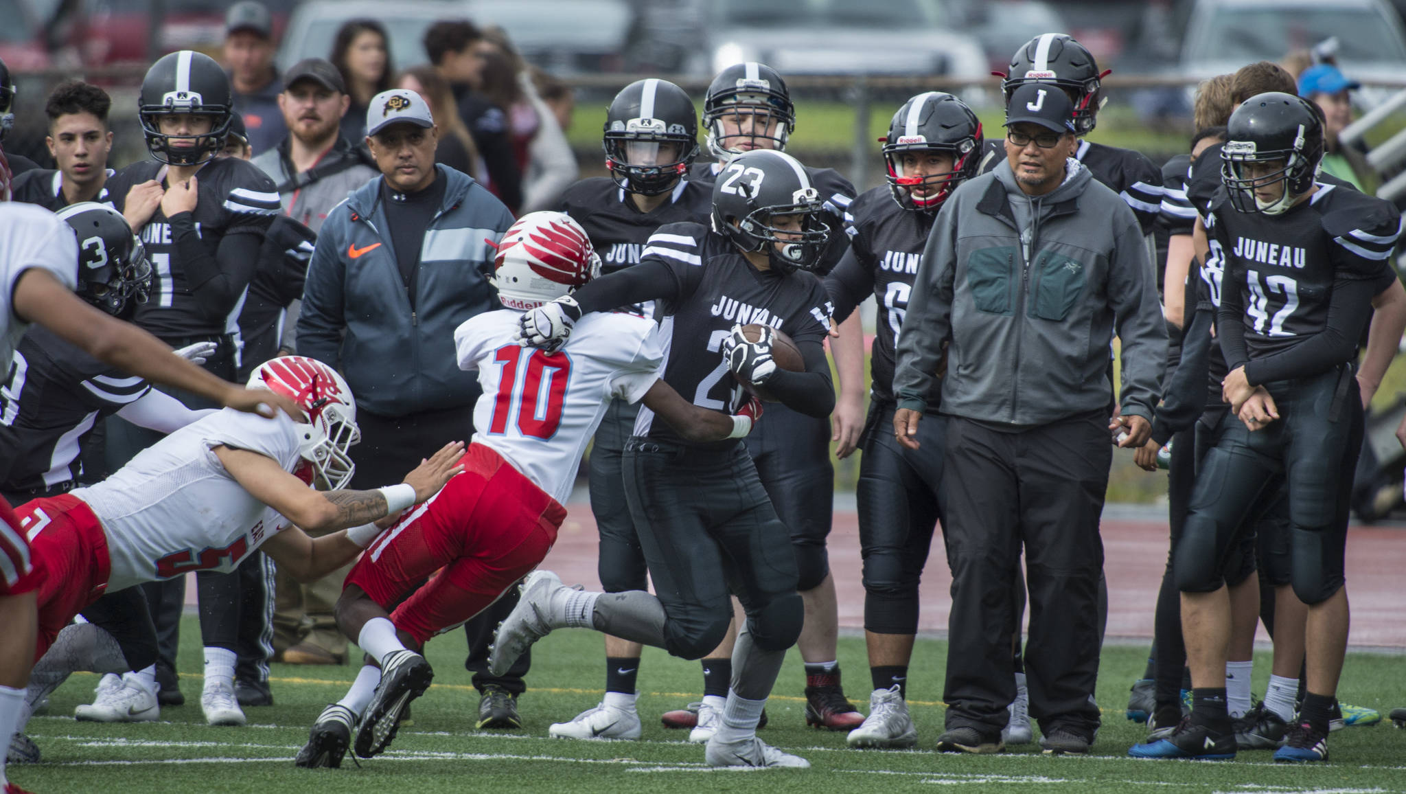 Juneau Football’s Cody Morehouse, center, is forced out of bounds by East’s Alex Hinton at Adair-Kennedy Memorial Field on Saturday, Aug. 25, 2018. East won 40-0. (Michael Penn | Juneau Empire)
