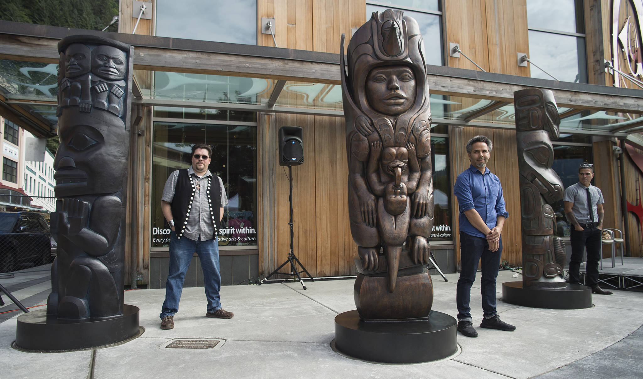 Tsimshian artist David R. Boxley, left, Tlingit artist Stephen Jackson, center, and Haida artist TJ Young, stand by their bronze house posts during an unveiling ceremony in front of the Walter Soboleff Center by Sealaska Heritage Institute on Sunday, Aug. 26, 2018. (Michael Penn | Juneau Empire)