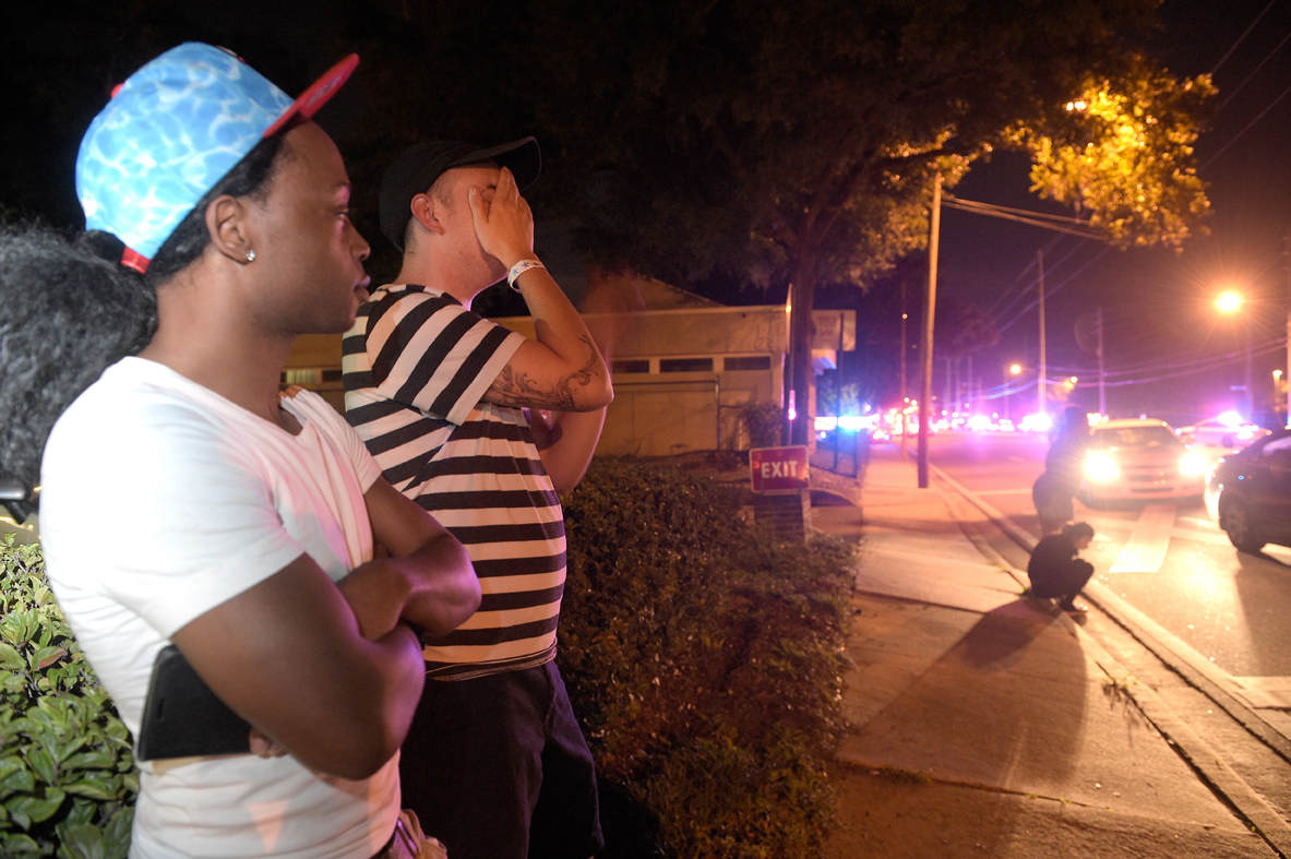Jermaine Towns, left, and Brandon Shuford wait down the street from a multiple shooting at a nightclub in Orlando, Fla., Sunday morning. Towns said his brother was in the club at the time. A gunman opened fire at a nightclub in central Florida, and multiple people have been wounded, police said Sunday.