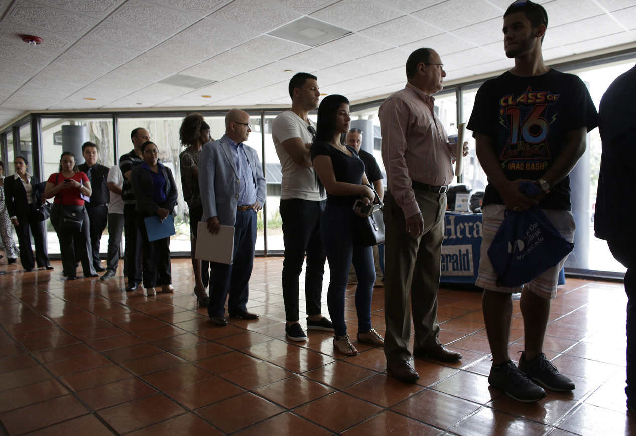 In this Tuesday, July 19, 2016, photo, people stand in line to register for a job fair in Miami Lakes, Florida.