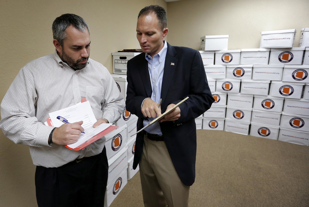 The Campaign to Regulate Marijuana Like Alcohol chairman J.P. Holyoak, hands over boxes of signatures to Arizona State Elections Director Eric Spencer, left, Thursday, June 30, 2016, in Phoenix. Organizers of the Campaign to Regulate Marijuana Like Alcohol delivered signatures to state officials in an effort for their proposal to qualify for the ballot in November.