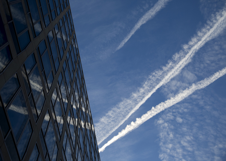 In this Jan. 23, 2015 file photo, airplane contrails are reflected in a building as they cross the early morning sky above Pennsylvania Ave. in Washington.