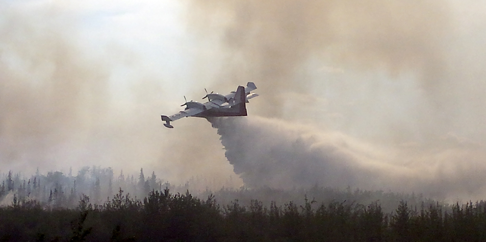 In this photo taken June 18, 2016, and provided by the Alaska Division of Forestry, a CL-415 water scooping aircraft drops its load on the Tetlin River Fire along the Tetlin, Alaska.