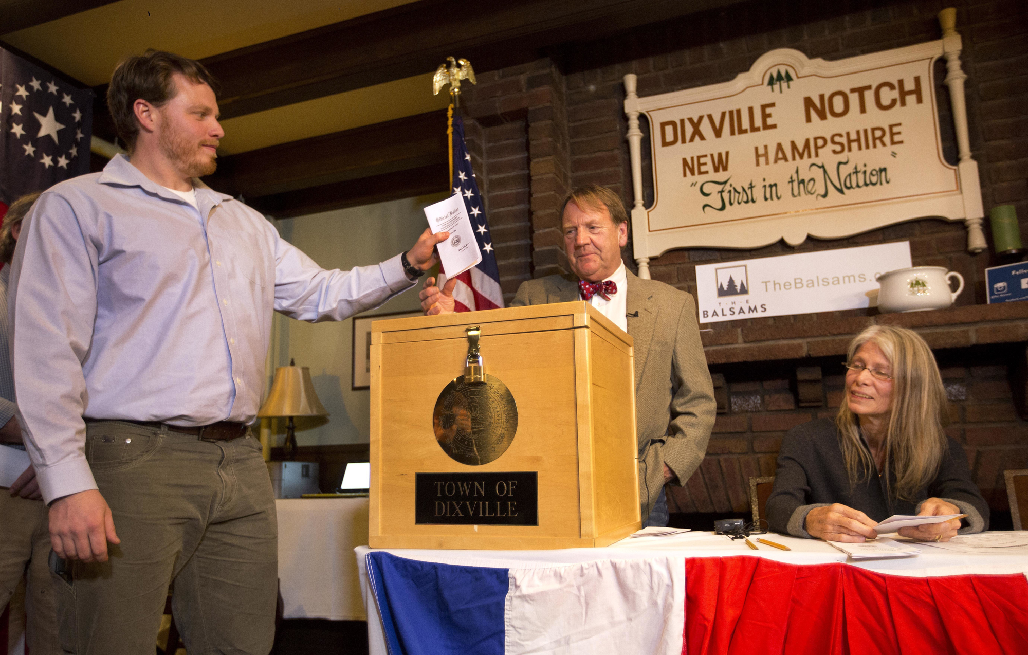 Dixville Notch's first voter Clay Smith drops his ballot into the box as moderator Tom Tillotson watches Tuesday, Nov. 8, 2016, in Dixville Notch, N.H.