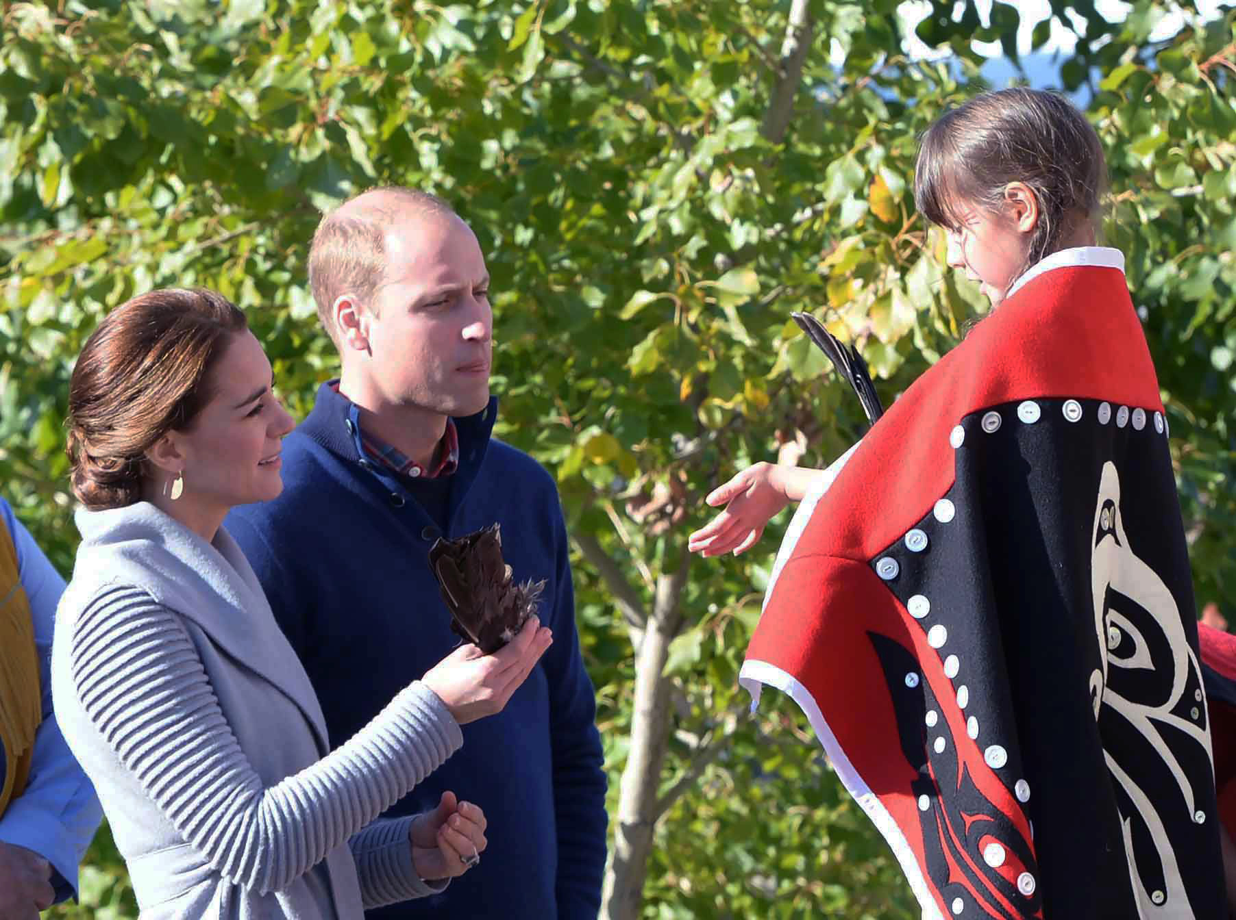 Kate, the Duchess of Cambridge holds an eagle feather given to her by a young girl as Prince William, the Duke of Cambridge, looks on during a welcoming ceremony in Carcross, Yukon, Wednesday.