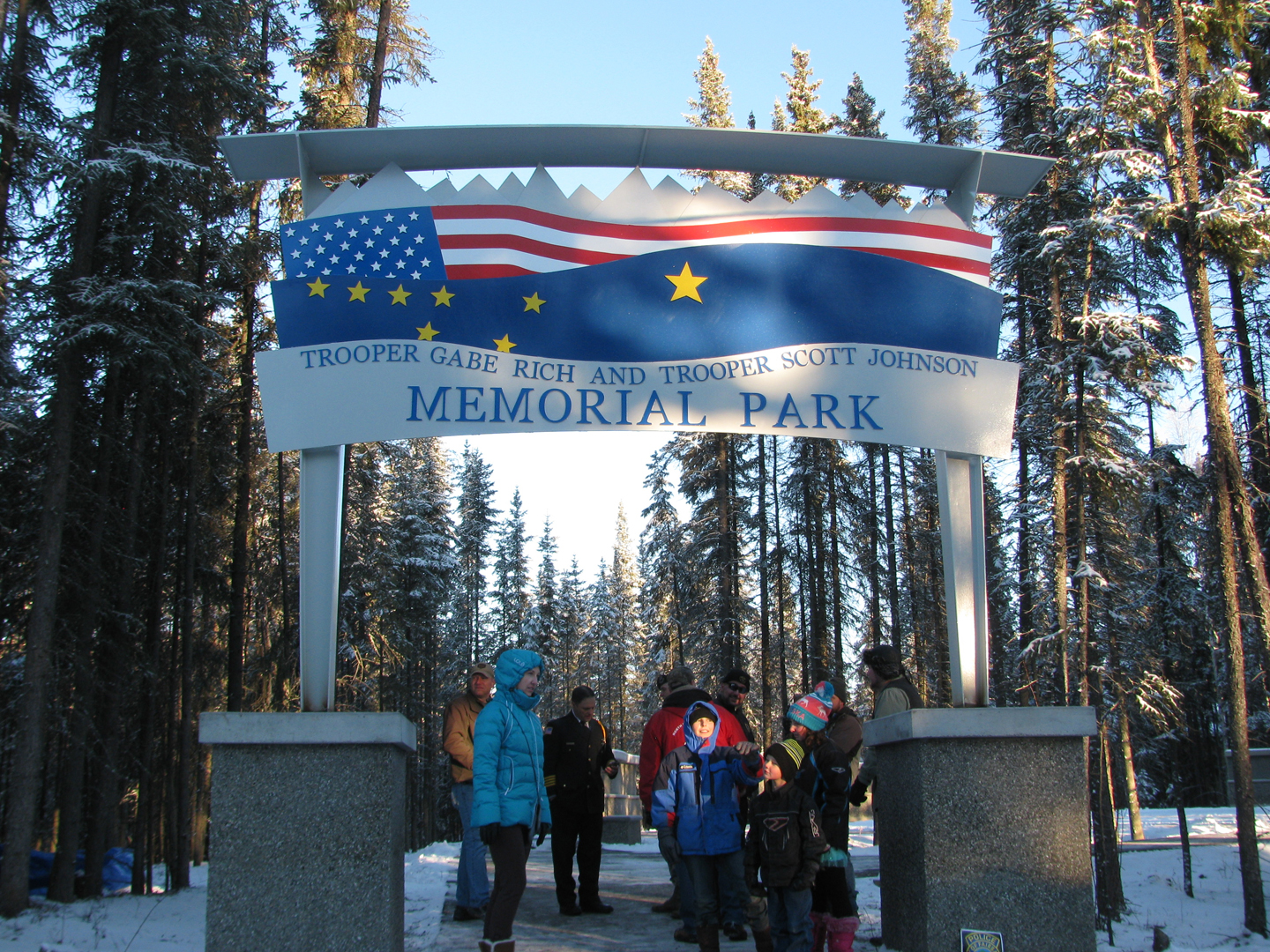 Residents gather underneath the newly unveiled Memorial Park arch in North Pole on Saturday. The arch honors Alaska State Trooper Gabe Rich and Sgt. Scott Johnson, both of whom were killed in action on May 1, 2014.