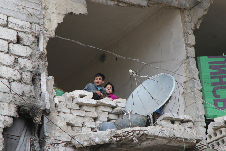 In this Feb. 11 file photo, children peer from a partially destroyed home in Aleppo, Syria.