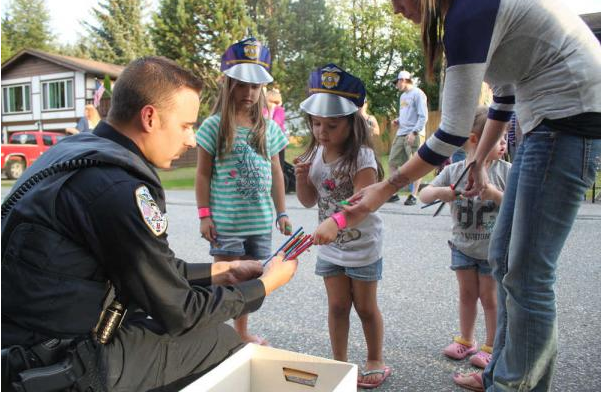 In this file photo from August 2015, Juneau Police Department Officer Ben Beck hands out pencils and paper police hats to neighborhood kids in the Mendenhall Valley during National Night Out.