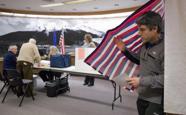 This file photo from March shows a Juneau voter exits a voting booth in the Assembly chambers after taking advantage of early voting.