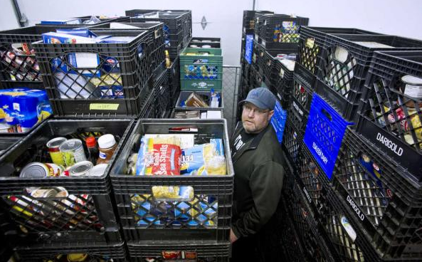 In this file photo from December 2015, Darren Adams, manager of the Southeast Alaska Food Bank, stands next to donated food at their warehouse on Crazy Horse Drive.