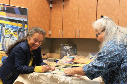 In this file photo from August, Clarissa Rizal, left, and Della Cheney, right, work on the "Weavers Across the Water" robe.