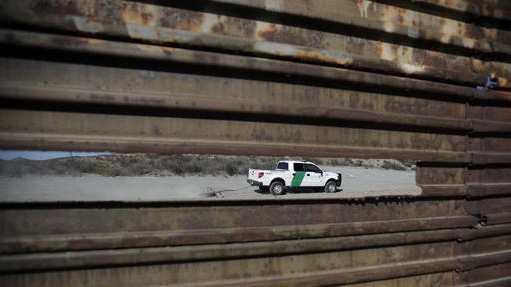 In this Nov. 9, 2016 photo, a Border Patrol vehicle drives by in Tecate, Calif., seen through a hole in the metal barrier that lines the border in Tecate, Mexico. U.S. President Donald Trump will direct the Homeland Security Department to start building a wall at the Mexican border. (Gregory Bull | The Associated Press file)