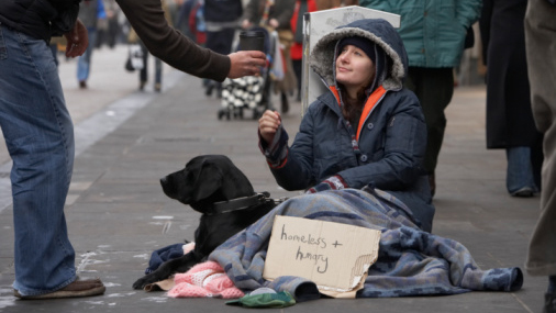 A passerby gives a homeless woman a cup of coffee. (Thinkstock file photo)