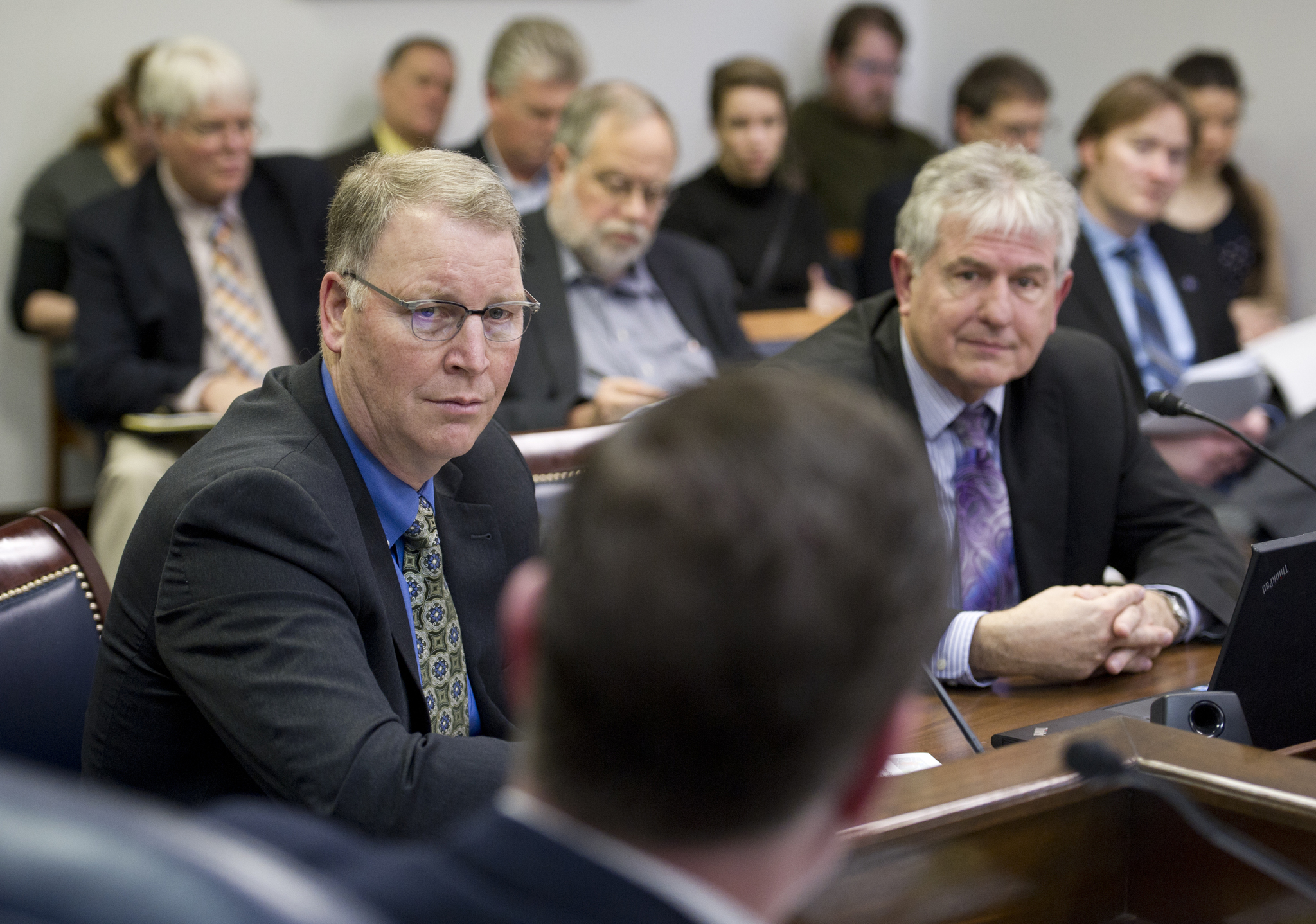 Marc Luiken, commissioner of the Department of Transportation and Public Facilities, left, and Jerry Burnett, deputy commissioner of the Department of Revenue, listen to a question by Rep. Chuck Kopp, R-Anchorage, foreground, as they present the governor&rsquo;s motor fuel tax bill in the House Transportation Committee at the Capitol on Tuesday. (Michael Penn | Juneau Empire)