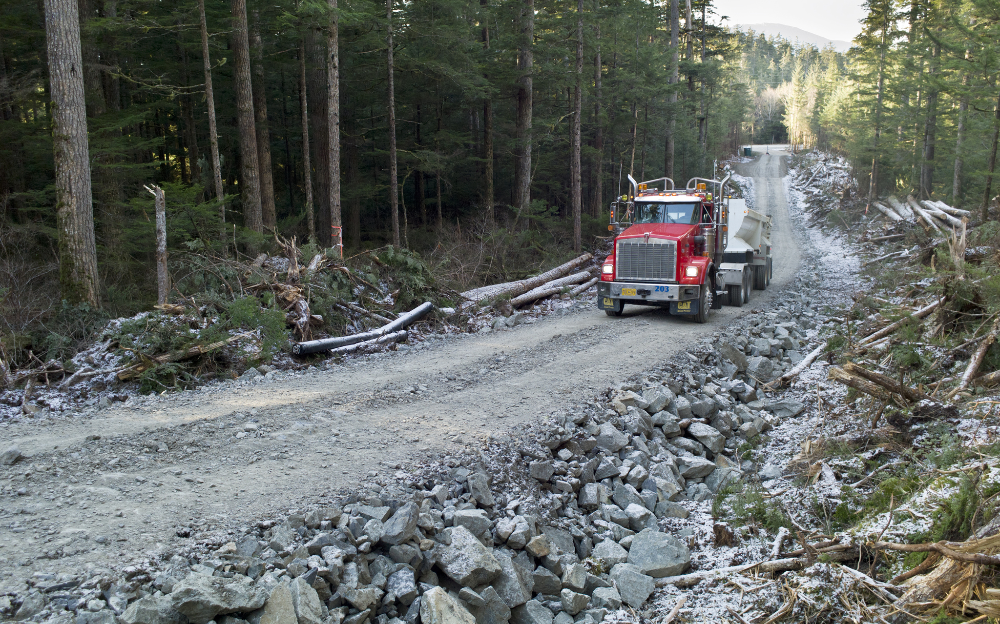A truck brings rock for construction of the new West Douglas Pioneer Road on Douglas Island on Friday. (Michael Penn | Juneau Empire)