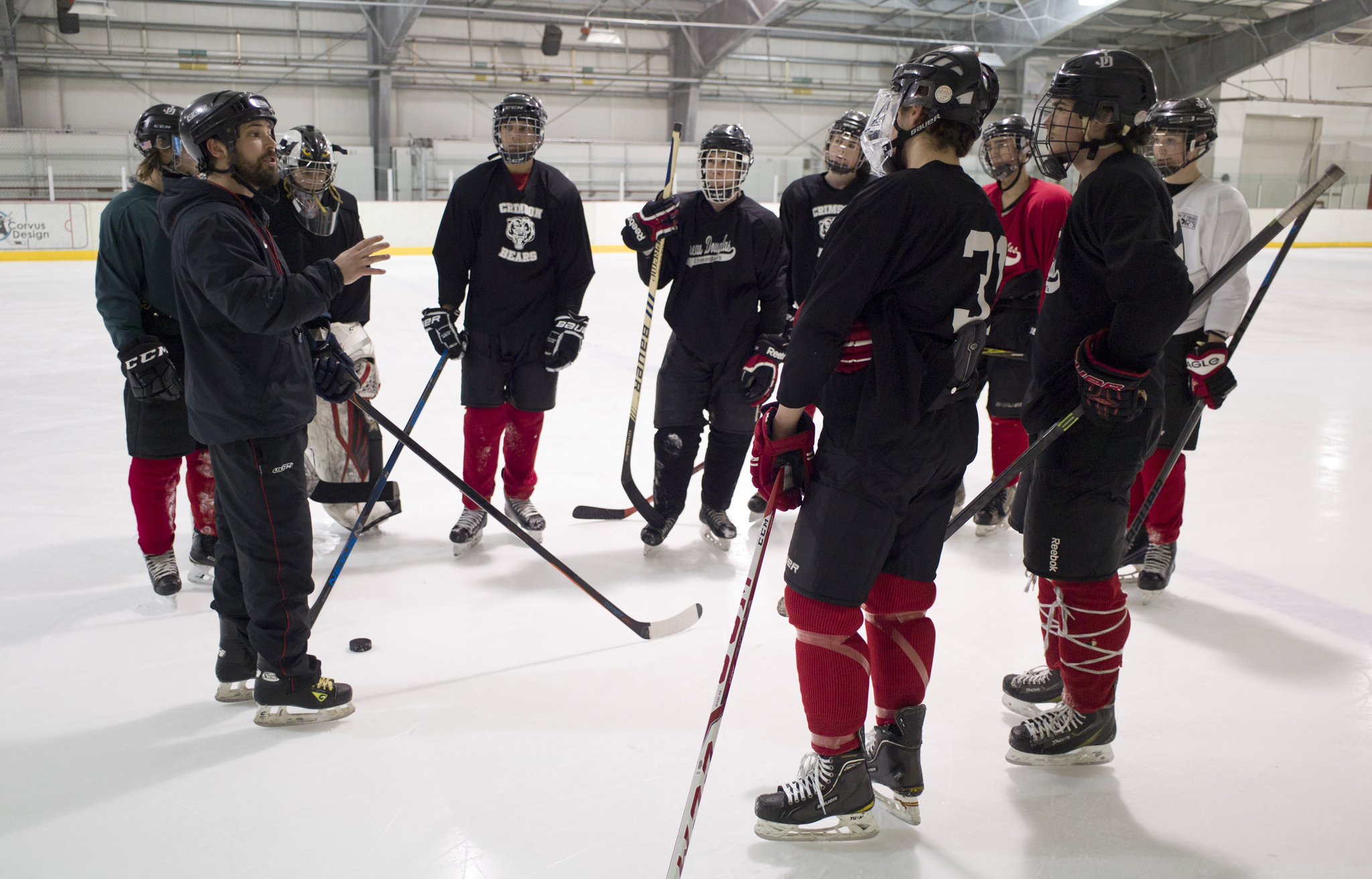 Juneau-Douglas High School hockey coach Luke Adams, left, speaks to players during a team practice at Treadwell Arena on Wednesday, Feb. 1. (Michael Penn | Juneau Empire File)