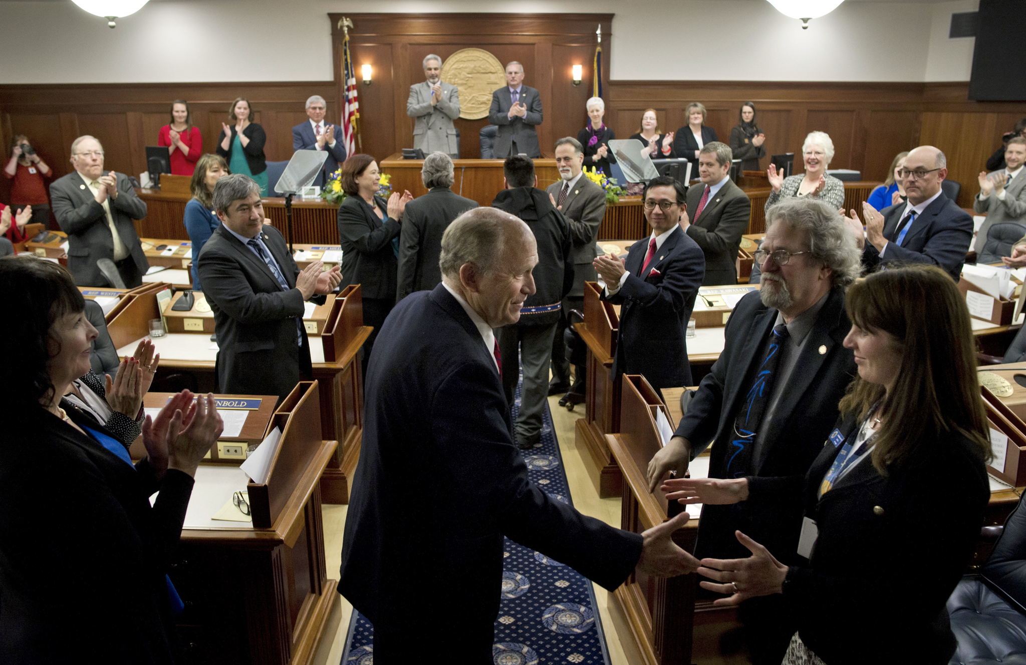 Gov. Bill Walker shakes hands with legislators as he enters the House chamber for his State of the State address on Jan. 18 before a joint session of the Alaska Legislature at the Capitol. Senate President Pete Kelly, R-Fairbanks, left, and Speaker of the House Bryce Edgmon, D-Dillingham, watch from the Speakers desk in the background. (Michael Penn | Juneau Empire)