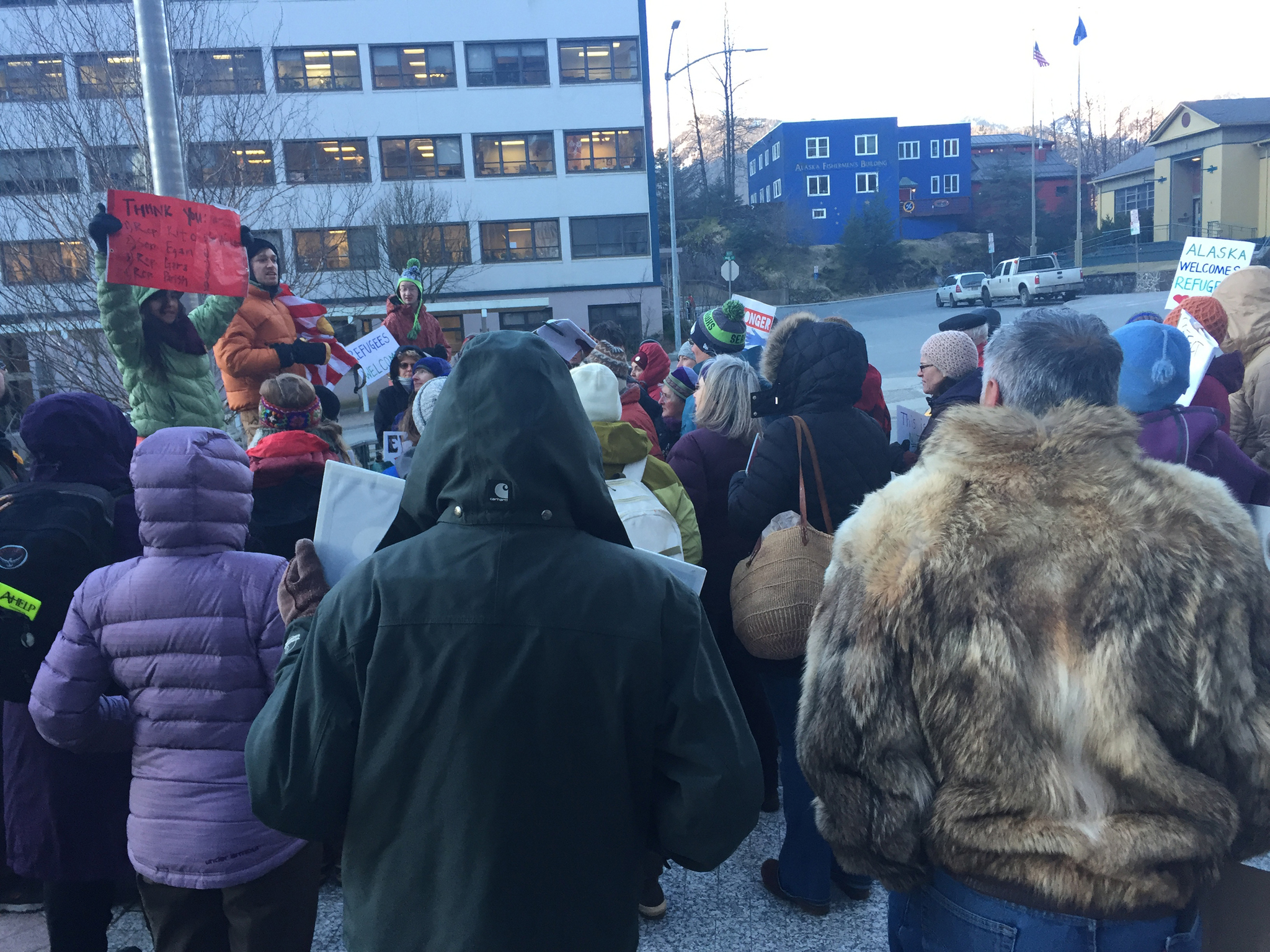 “Stand with Refugees and Immigrants” event organizers Jill Weitz (with red sign) and Daniel Kirkwood (orange jacket) speak with attendees prior to dispersing around 8:30 a.m. Monday. (Mary Catharine Martin | Juneau Empire)