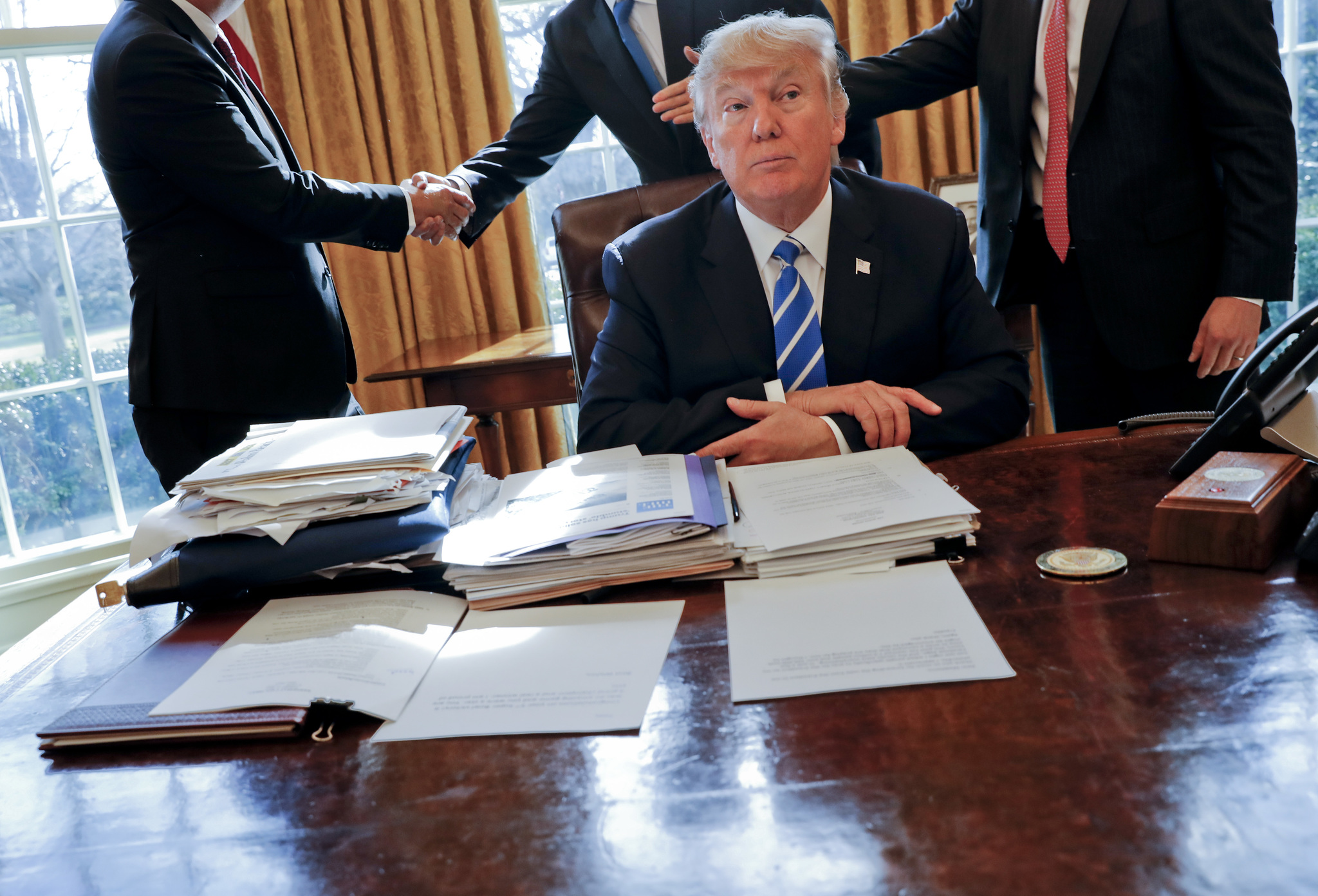 President Donald Trump sits at his desk after a meeting with Intel CEO Brian Krzanich, left, and members of his staff in the Oval Office of the White House in Washington on Wednesday. (Pablo Martinez Monsivais | The Associated Press)