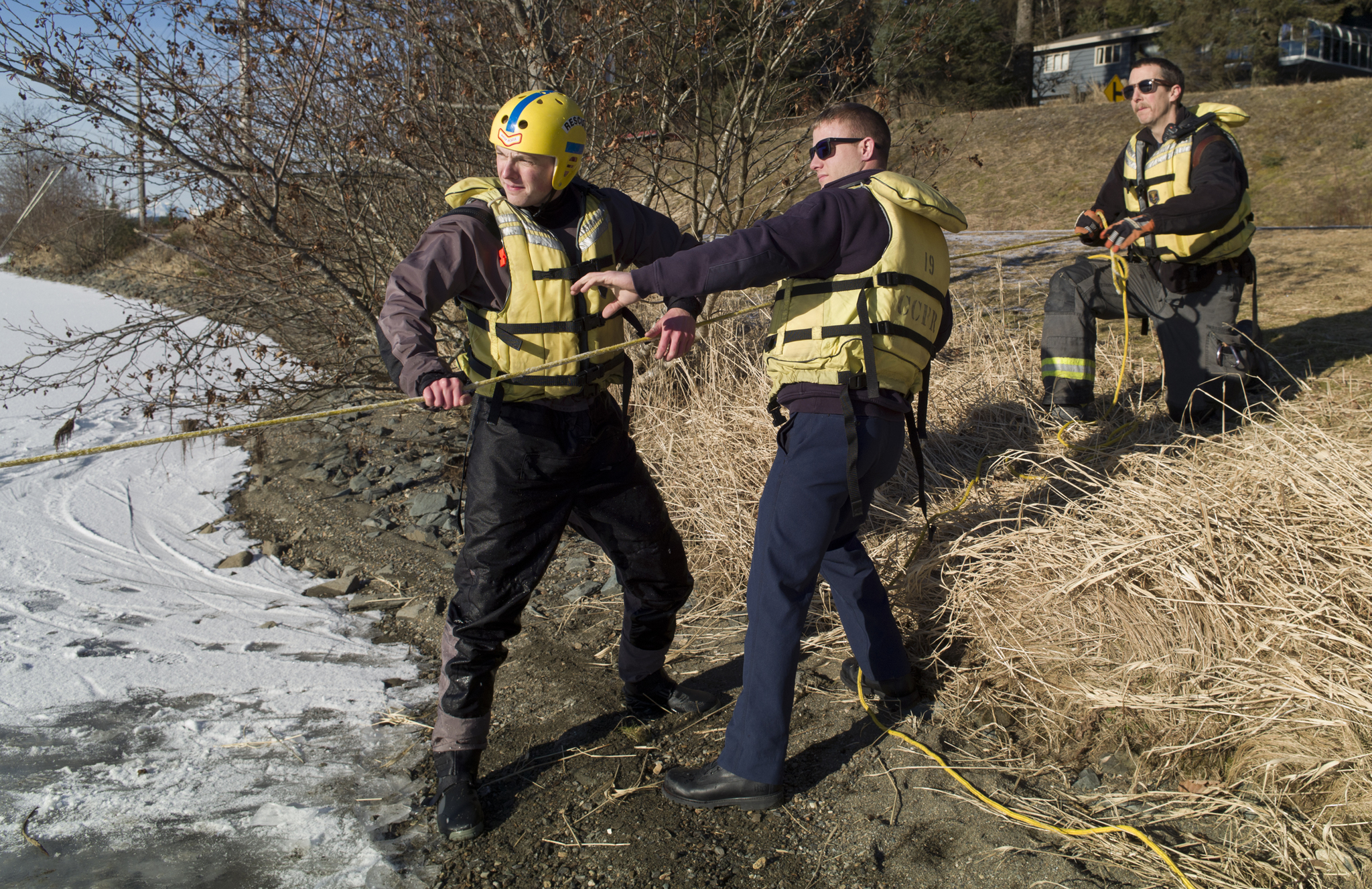 Capital City Fire/Rescue firefighter Capt. Noah Jenkins, right, firefighter Andrew Bishop, center, and volunteer firefighter Chad Gustafson participate during an ice rescue training at Twin Lakes on Thursday. (Michael Penn | Juneau Empire)