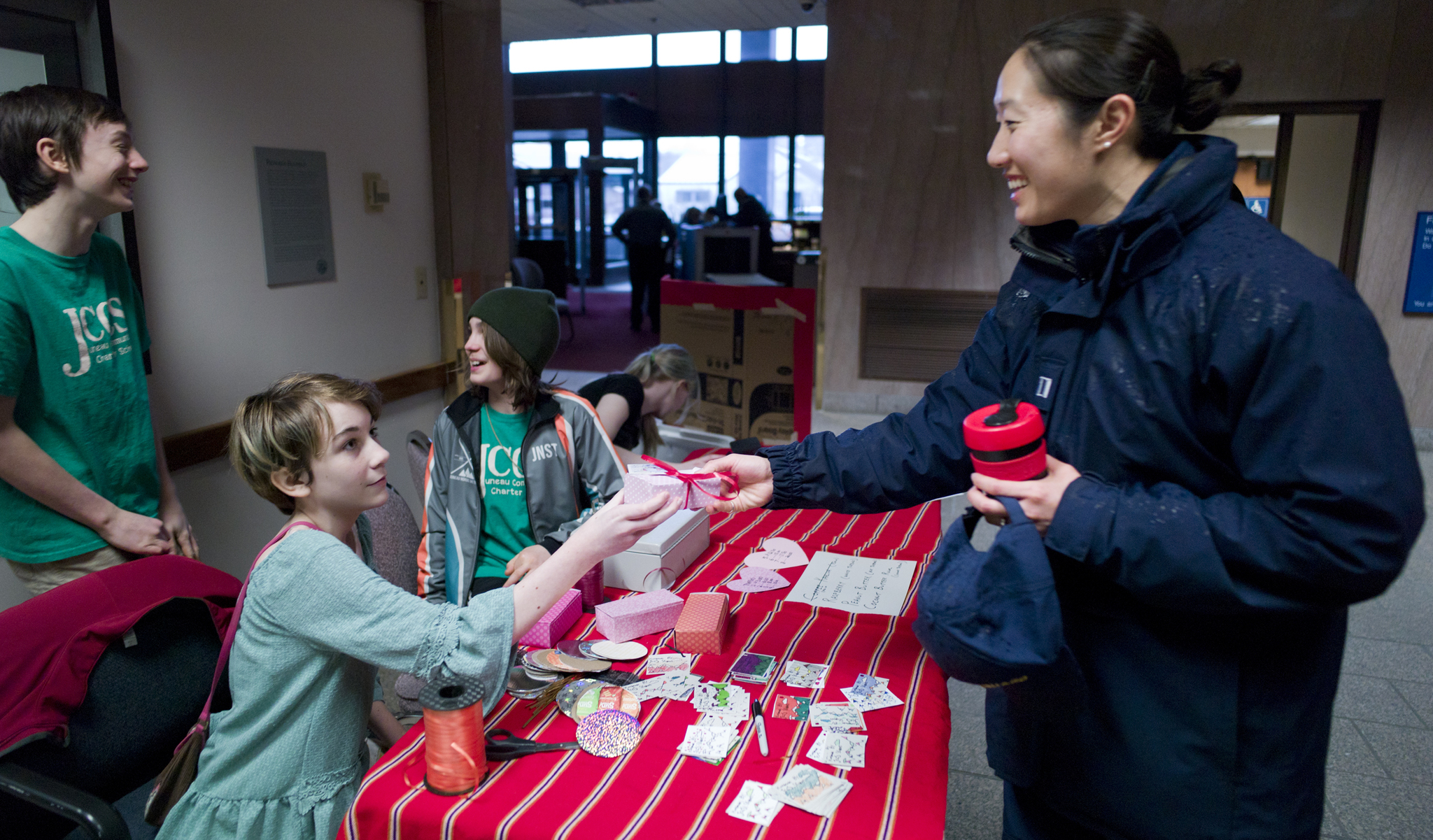 Yvonne Yang, right, is handed a box of chocolate truffles by Juneau Community Charter School eighth-grader Rylee Caron during a Valentine’s Day sale Tuesday at the Federal Building. Proceeds for the sale of about 700 truffles will help pay for the eighth grade class to visit Fairbanks and Denali National Park in May. Other students pictured are Adam Bishop, left, Callahan Croteau and Karrie McVey. (Michael Penn | Juneau Empire)