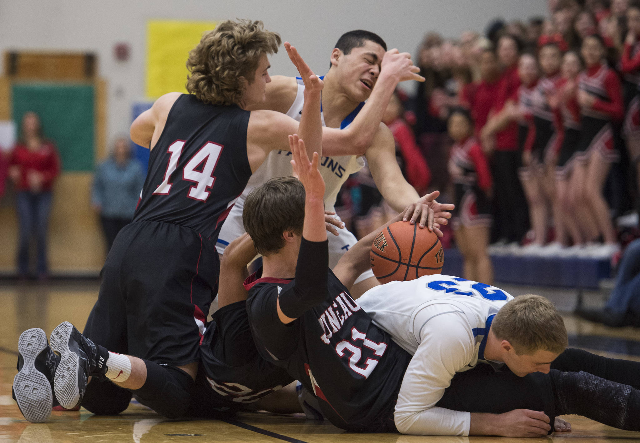 Juneau-Douglas’s Kasey Watts, Ulyx Bohulano and Bryce Swofford pile up with Thunder Mountain’s Roy Tupou and Riley Olson during a loose ball at TMHS on Friday, March 3, 2017. JDHS won 46-40. (Michael Penn | Juneau Empire)