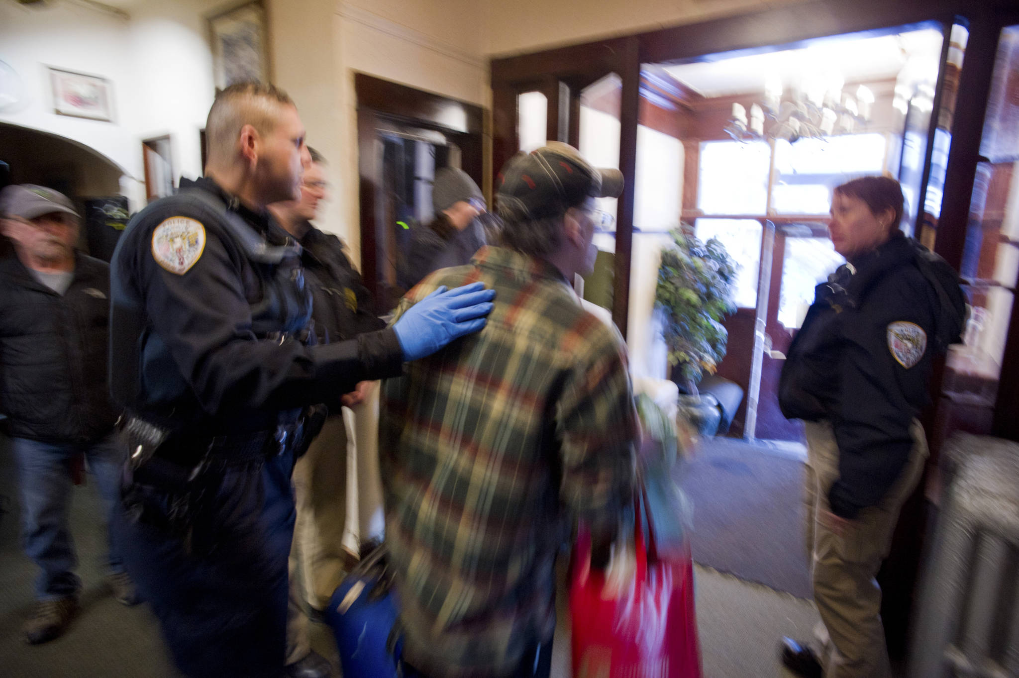 Juneau police officers escort a tenant out of the Bergmann Hotel as the city closed the building for health and safety reasons on Friday. (Michael Penn | Juneau Empire)