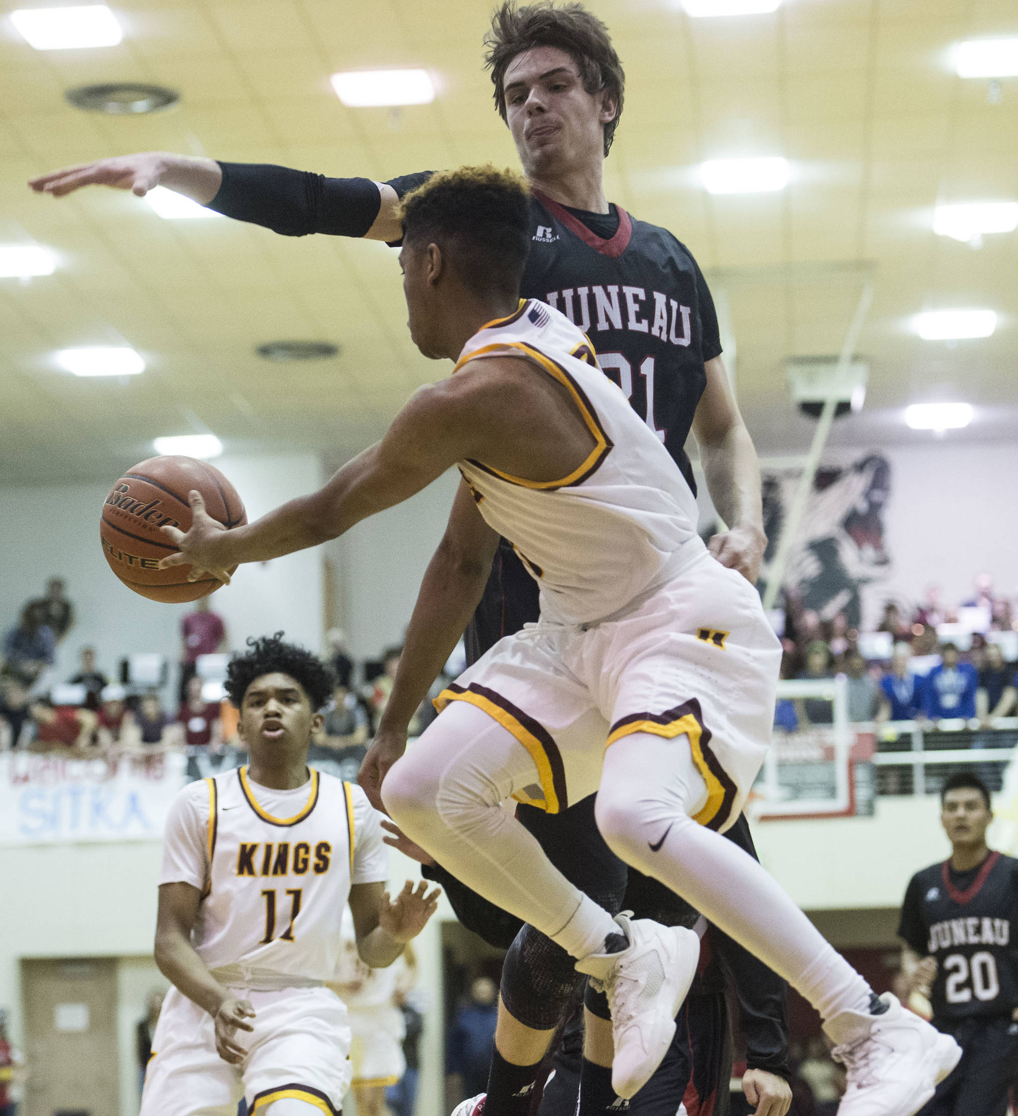 Ketchikan’s Marcus Lee passes to his brother, Chris, around Juneau-Douglas’ Bryce Swofford during the Region V Basketball finals at JDHS on Friday. (Michael Penn | Juneau Empire)