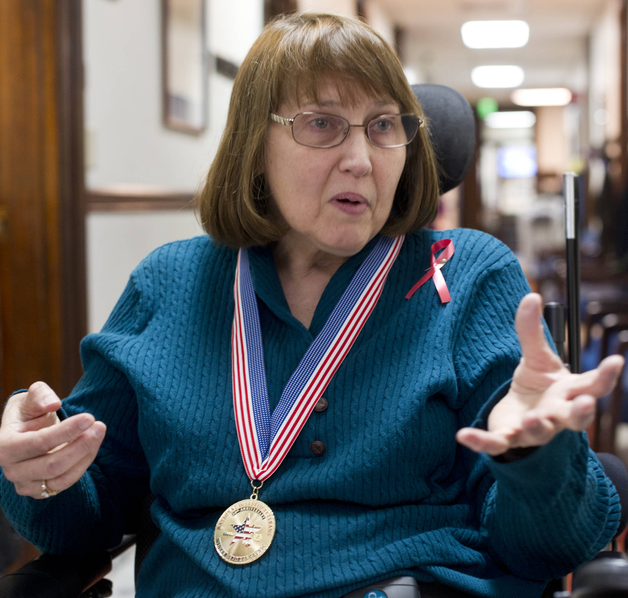 Susan Macaulay, an Air Force Veteran from Juneau, speaks with Rep. Justin Parish, D-Juneau, at the Capitol on Wednesday. Macaulay is wearing her National Disabled Veterans Winter Sports Clinic’s 30th Anniverary medal. (Michael Penn | Juneau Empire)